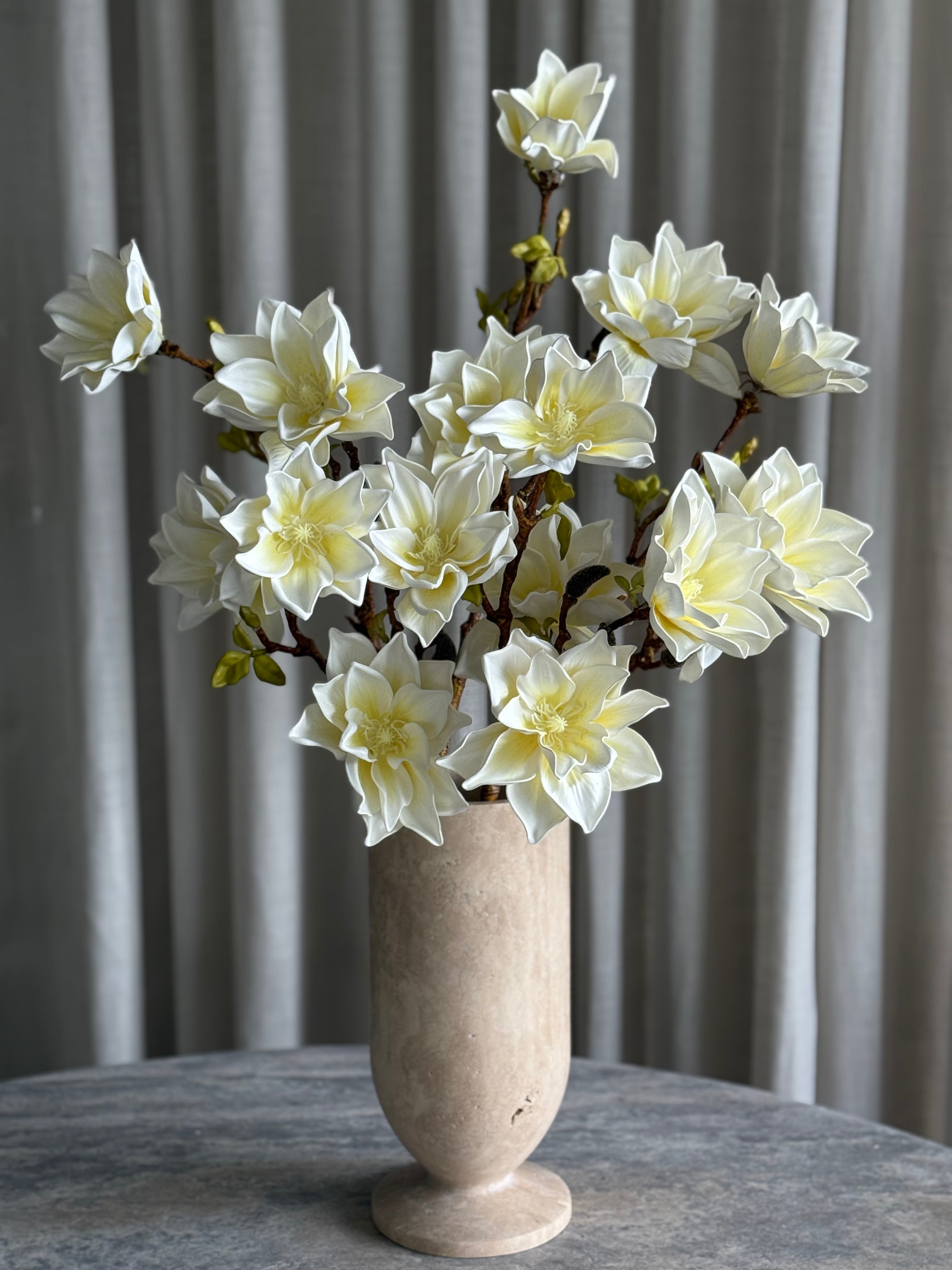 Magnoliabukett hvit i vase — lyse kronblader åpner seg langs organiske grener med naturlig tekstur