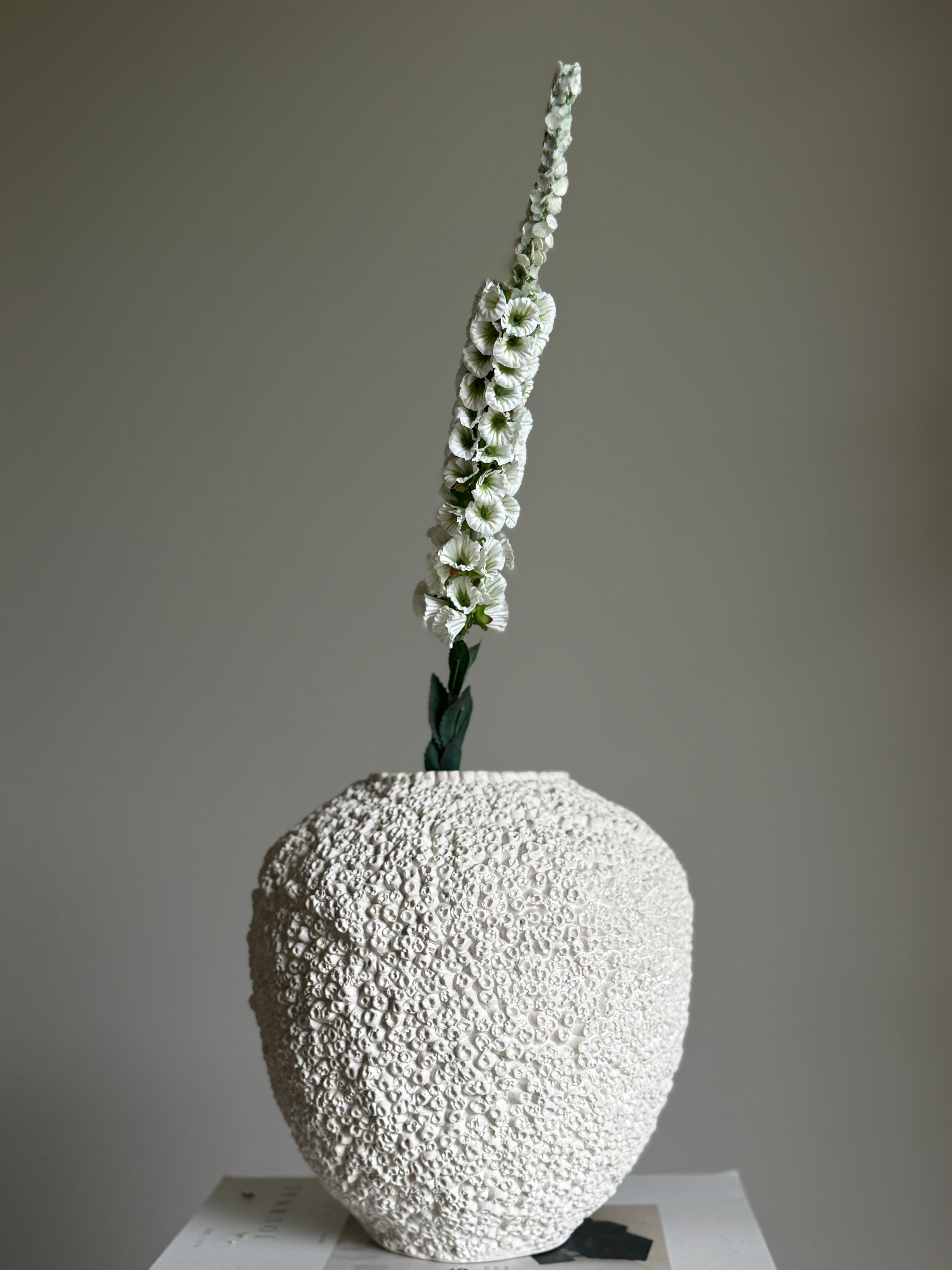 Revebjelle hvit kunstig blomsterstilk med hvite blomster i vertikal formasjon og grønne detaljer