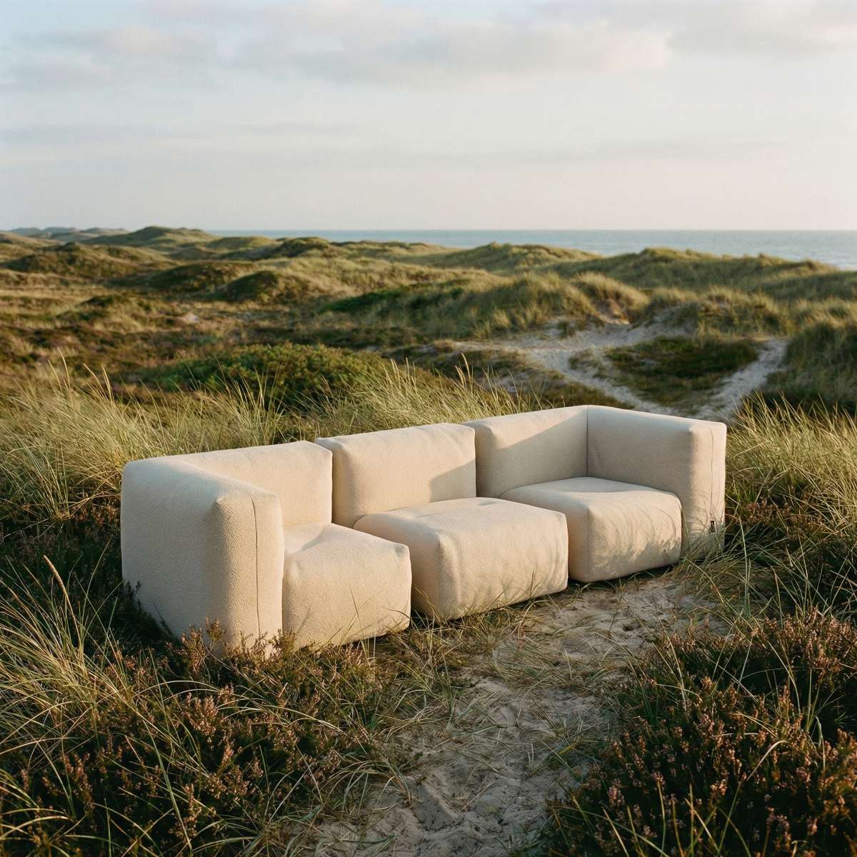 Soft 3 seter beige utesofa sett fra siden – formstabil silhuett og jevn beige finish under åpen himmel