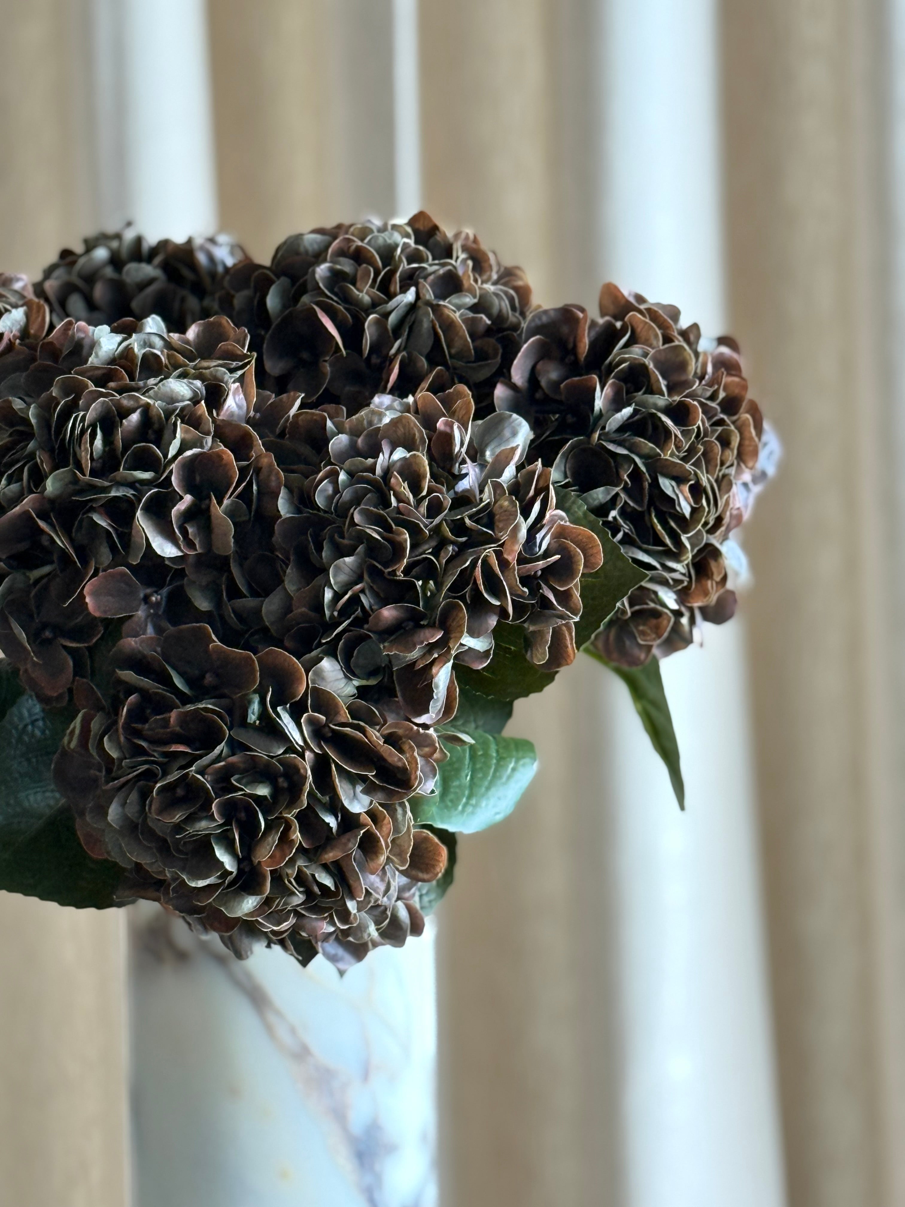 Nærbilde av kunstig hortensia mørk brun med tett tekstur av kronblader og naturlig farge-overgang